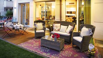 An outdoor seating area with wicker furniture, a glass-top coffee table, and a decorative gnome.