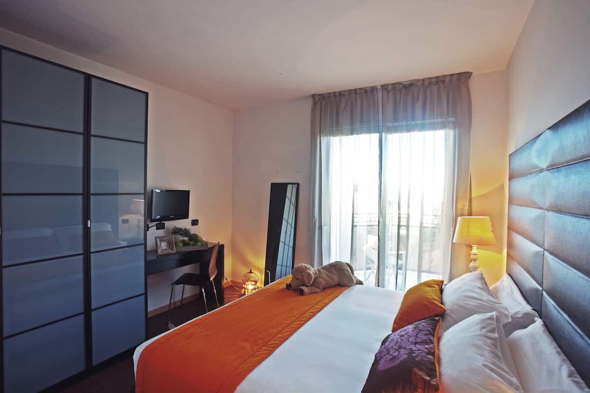 A hotel room with a bed, a desk, a television, and a window with curtains.
