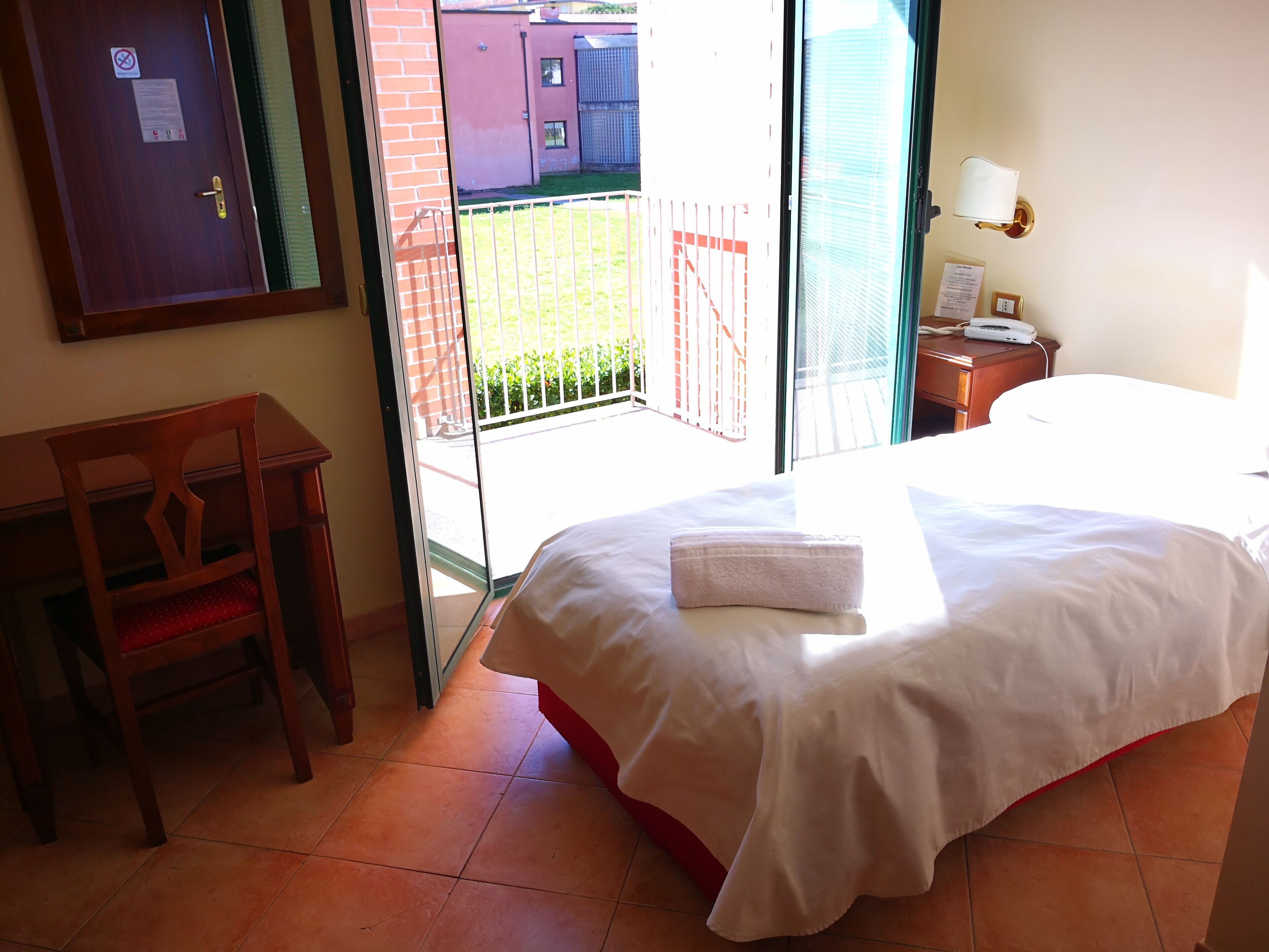 A hotel room with a bed, a desk, and a view of the outside.
