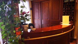 A reception desk with a vase of flowers, a bowl of fruit, and a plant. - Casa Betania (Pisa)