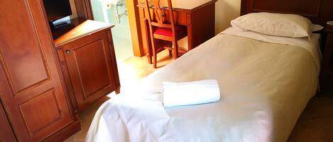 Habitación de hotel con cama, escritorio, silla, televisor y ventana.