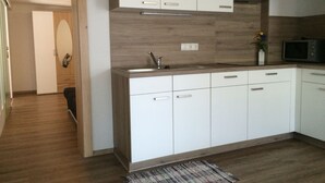 A modern kitchen with white cabinets, a wooden countertop, and a built-in microwave. - Sonnenhang (Soelden)