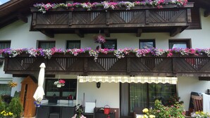 A two-story building with balconies adorned with colorful flowers, a sign reading "Haus Sonnenhang," and outdoor seating with a table and chairs. - Sonnenhang (Soelden)