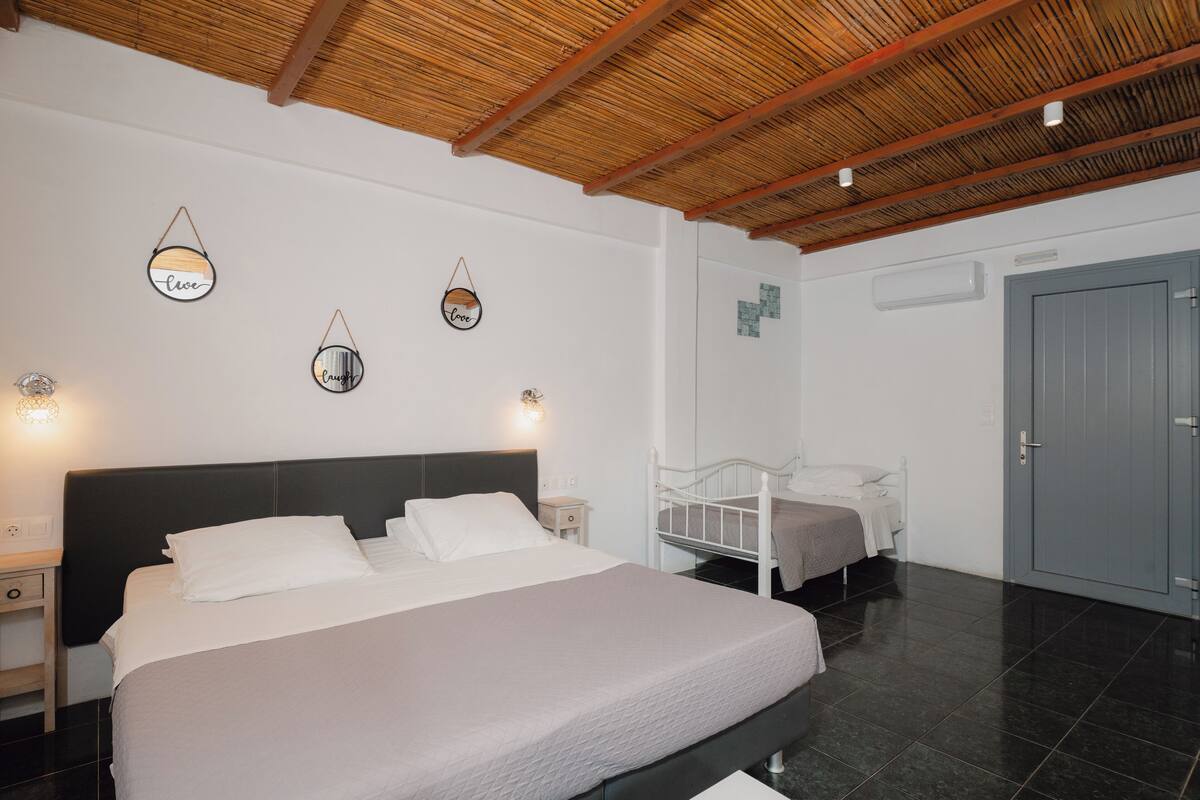 A bedroom with a large bed, bedside tables, a wardrobe, and a ceiling with wooden beams.