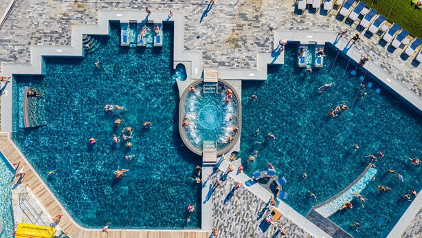 A large outdoor swimming pool with multiple diving platforms and a central hot tub area. - Camping Village Baia Blu La Tortuga (Aglientu)