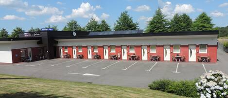 A motel with a parking lot, outdoor seating, and a garden.