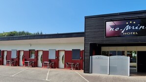Un hotel con fachada moderna, varias habitaciones y un estacionamiento.