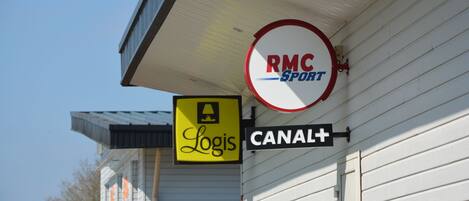 A building with signs for 'Logis' and 'RMC Sport' along with a directional sign for 'CANAL+'.