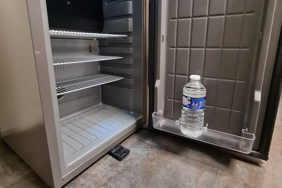 An open refrigerator with shelves and a water dispenser.