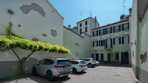Una calle estrecha con coches estacionados y un edificio con un gran mural.
