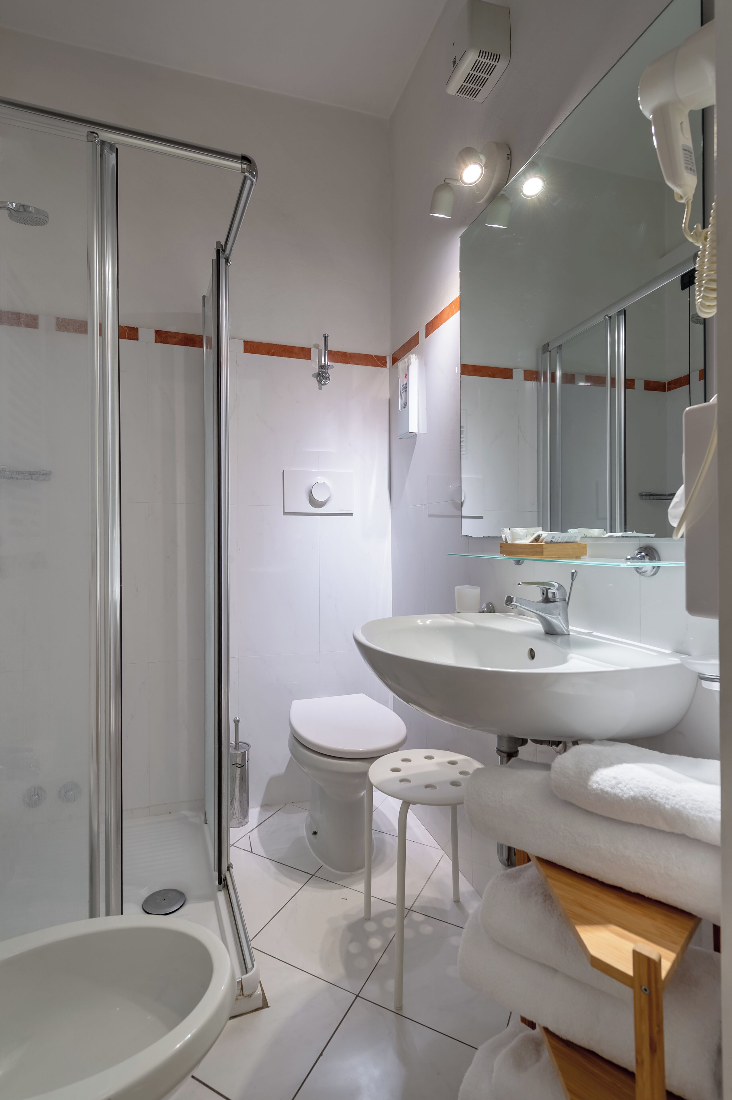 A modern bathroom with a glass-enclosed shower, a white sink, a toilet, and a mirror above the sink.
