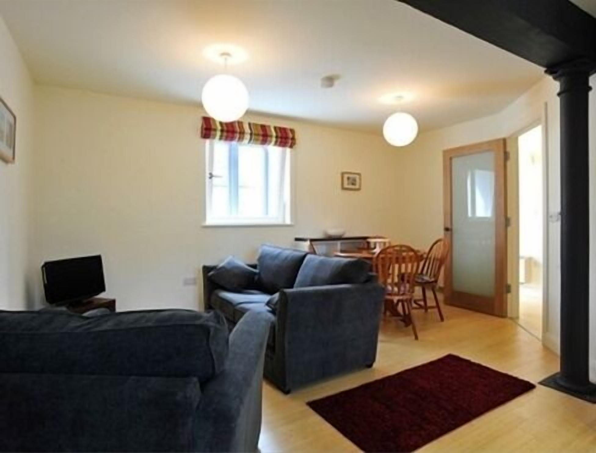 A living room with a sofa, a TV, and a dining area with chairs and a table.
