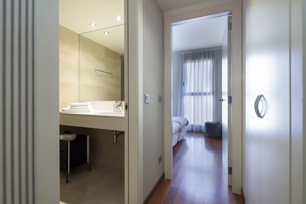 A modern hotel room with a bathroom, a bed, and a view of the outside.
