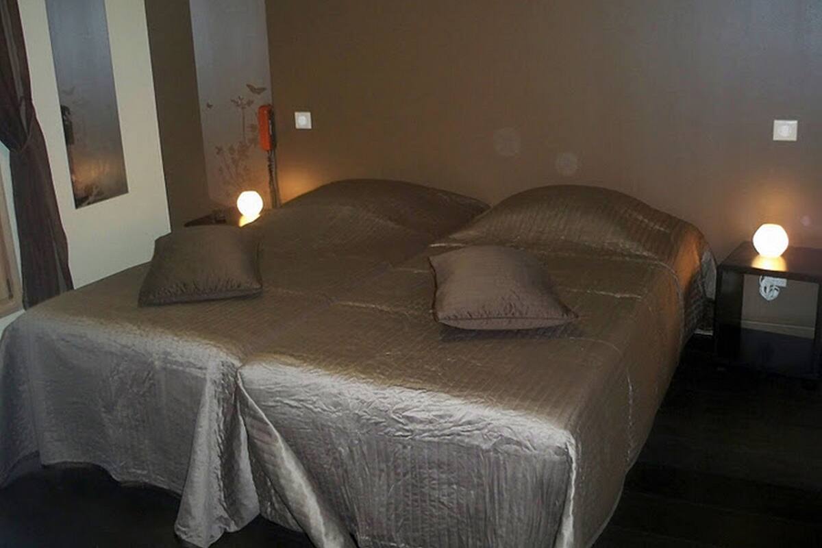 A bedroom with a large bed, two bedside tables, and a wall-mounted light fixture.