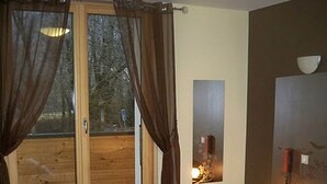 A bedroom with a large window, wooden flooring, and a bed with pillows. - Au Gai Soleil du Mont Aiguille (Chichilianne)