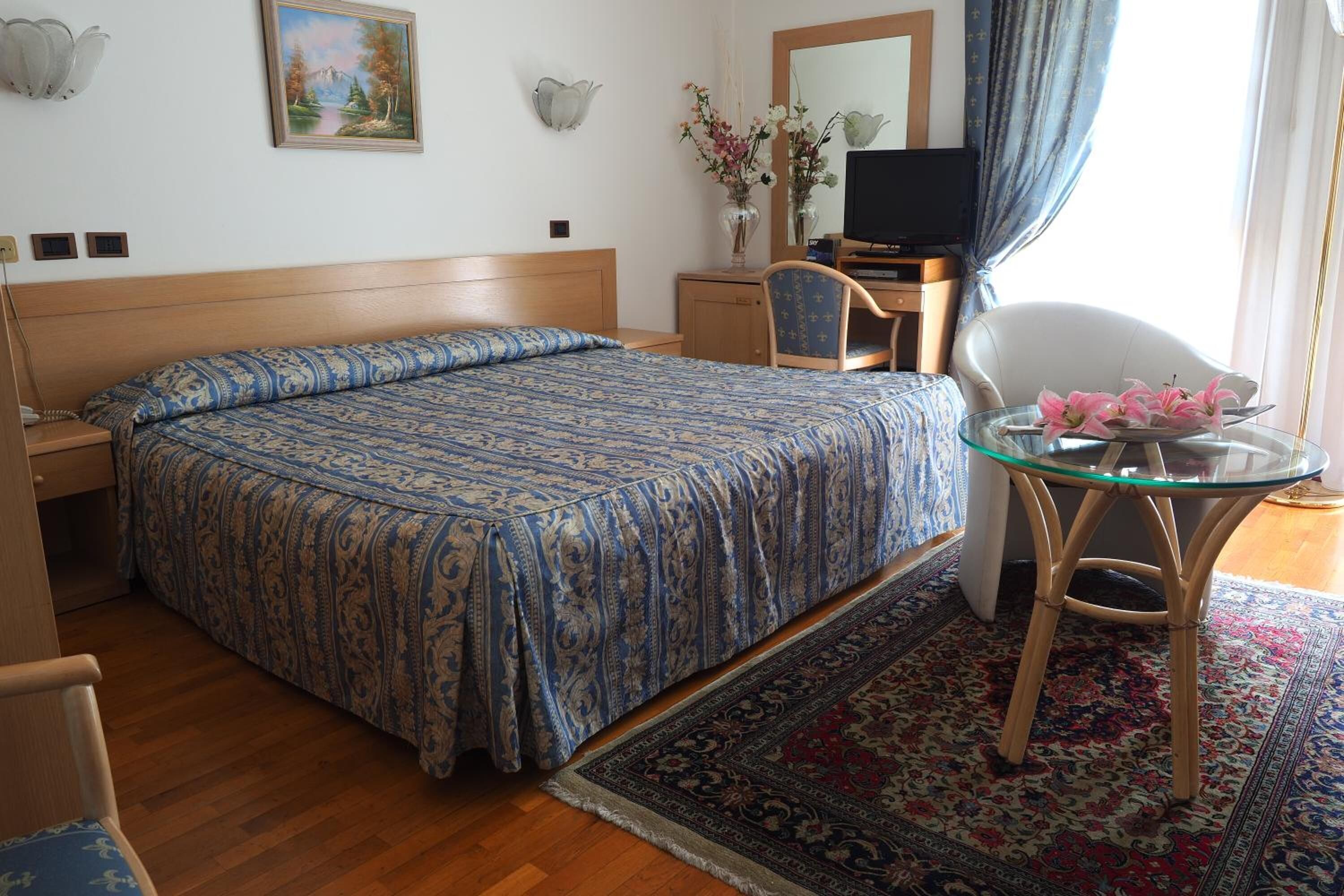 Un dormitorio con una cama grande, un escritorio, una silla y un televisor.