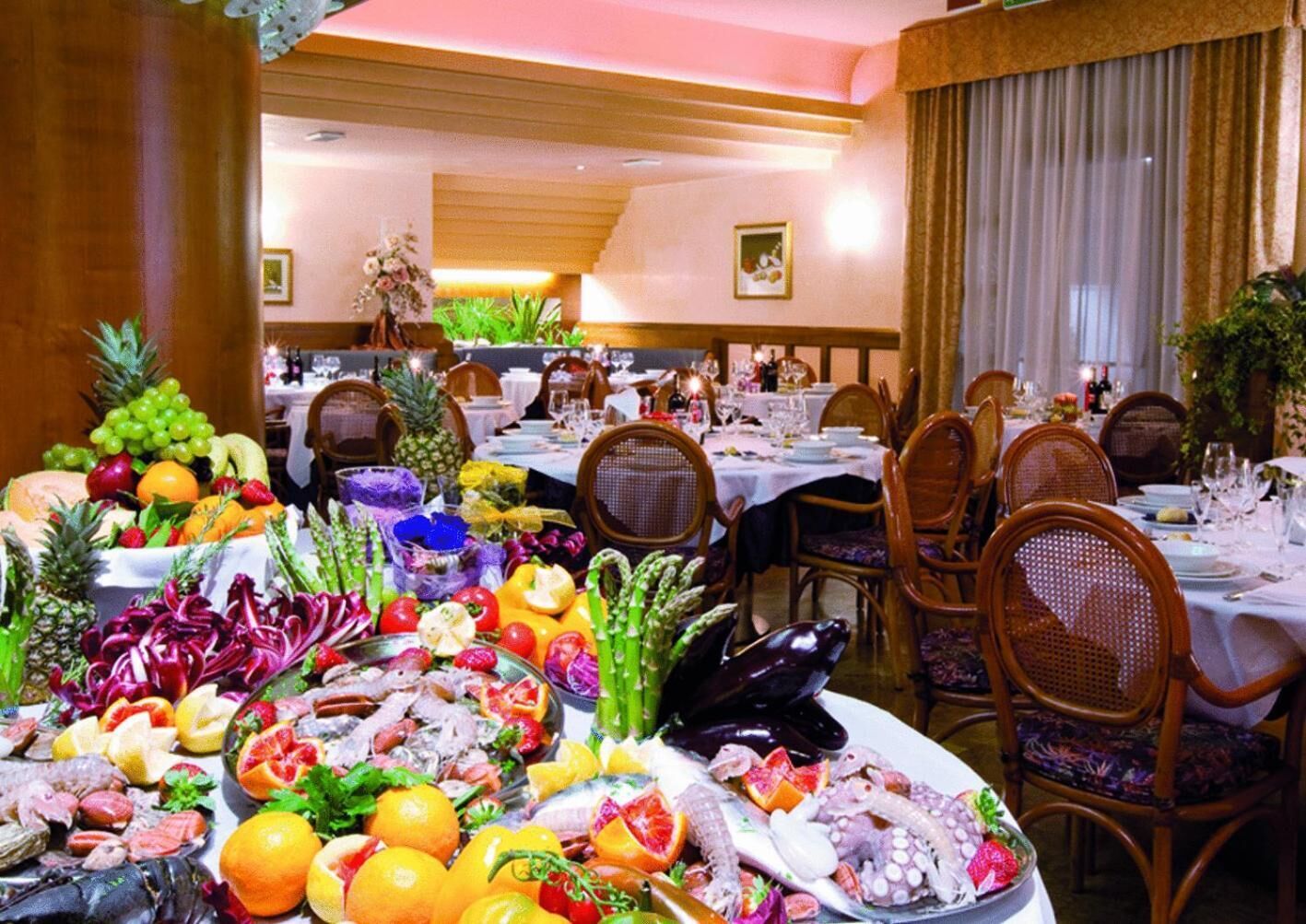Un espace repas avec plusieurs tables dressées pour le repas, où l’on peut admirer une variété de fruits de mer et de fruits frais.