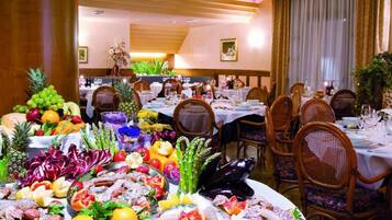Un espace repas avec plusieurs tables dressées pour le repas, où l’on peut admirer une variété de fruits de mer et de fruits frais.