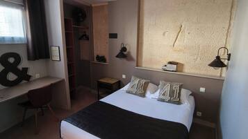 Ein Schlafzimmer mit Bett, Schreibtisch, Stuhl, Kleiderschrank und einem großen Fenster.