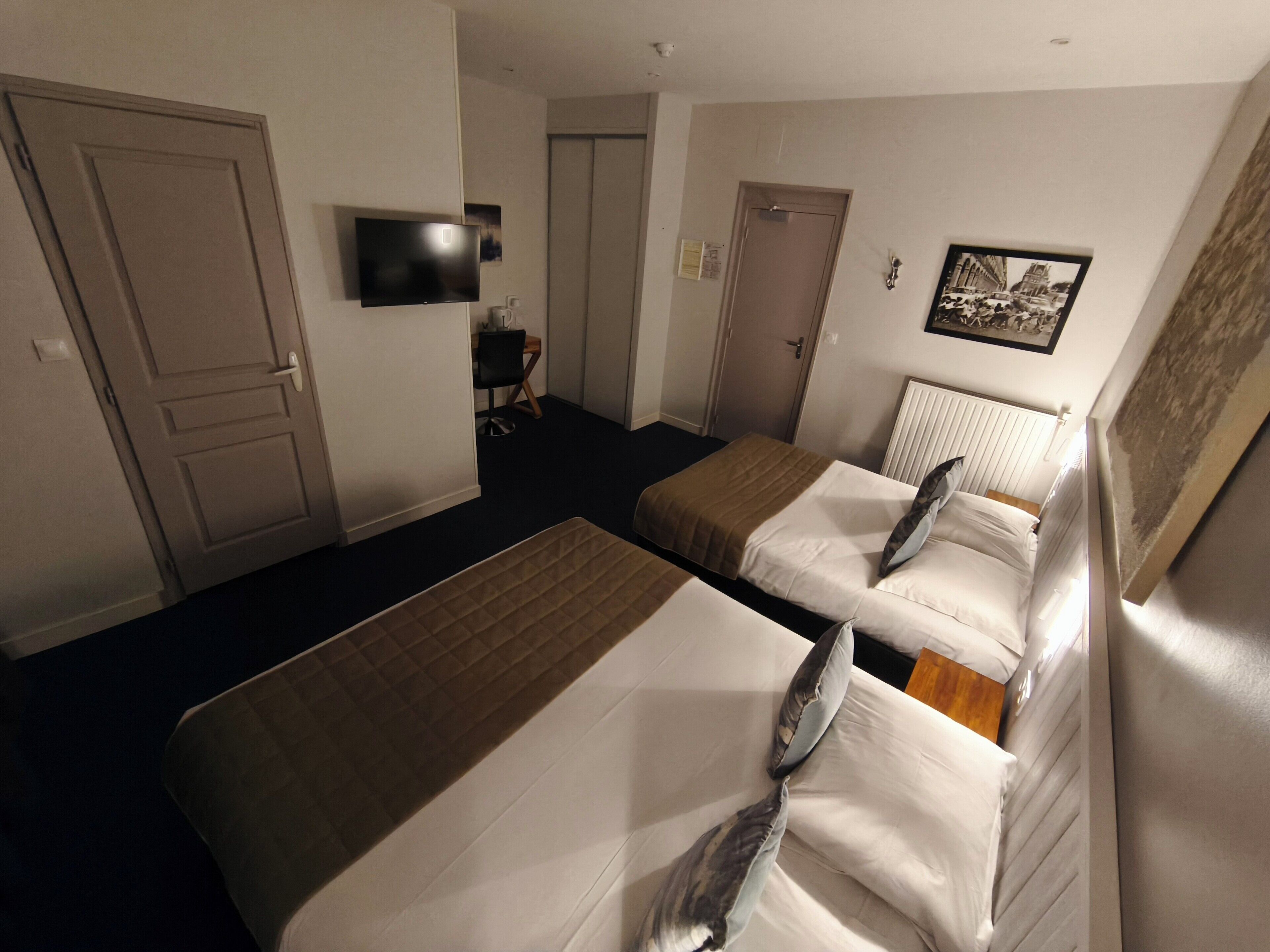A hotel room with two beds, a TV, a desk, and a chair.