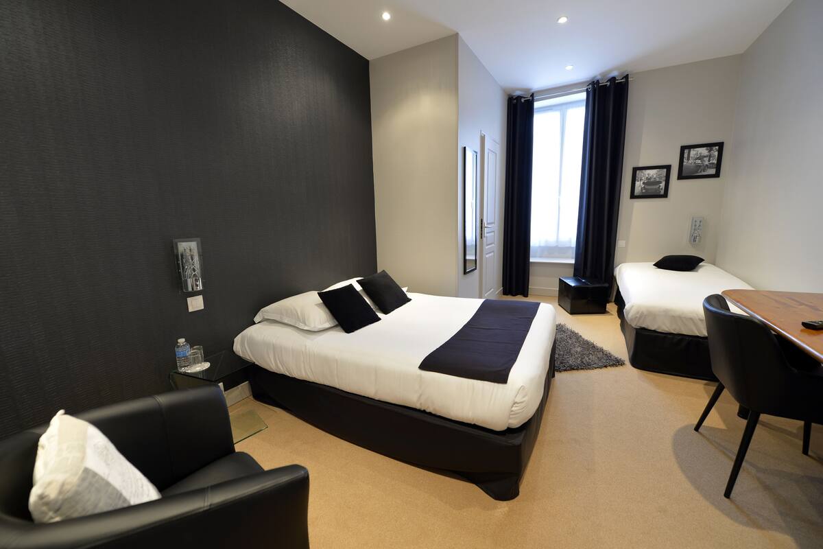 Una habitación de hotel moderna con una cama grande, una cama más pequeña, un escritorio y una silla.