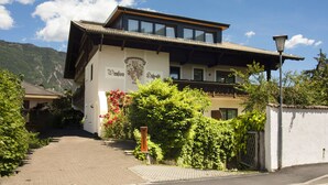 A building with a prominent sign, a balcony, and a mountain backdrop. - Pension Hilpold (Lana)