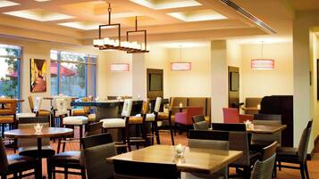 A restaurant with multiple tables and chairs, a ceiling with skylights, and a view of the outdoors.