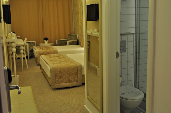 A hotel room with two beds, a desk, a chair, a TV, and a bathroom with a shower and toilet. - Hotel Edirne Palace (Edirne)