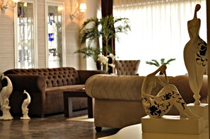A living room with a brown sofa, a beige sofa, and a white sculpture. - Hotel Edirne Palace (Edirne)