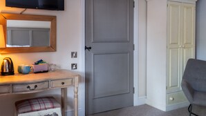 A room with a wooden desk, a television, a grey door, and a grey chair. - The Crown & Horns (Newbury)