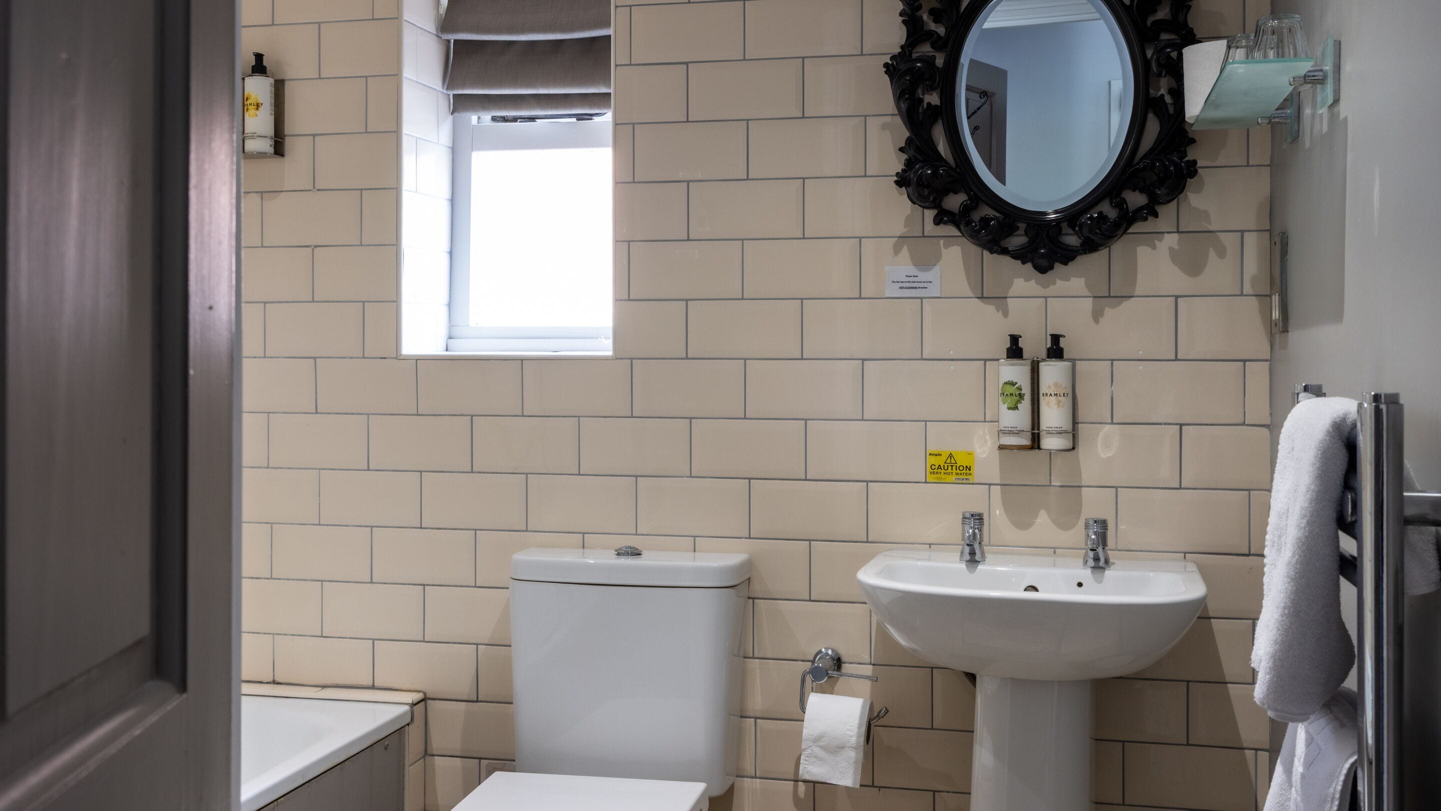 Un baño con inodoro, lavamanos, espejo y ventana.