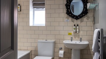 Un baño con inodoro, lavamanos, espejo y ventana.
