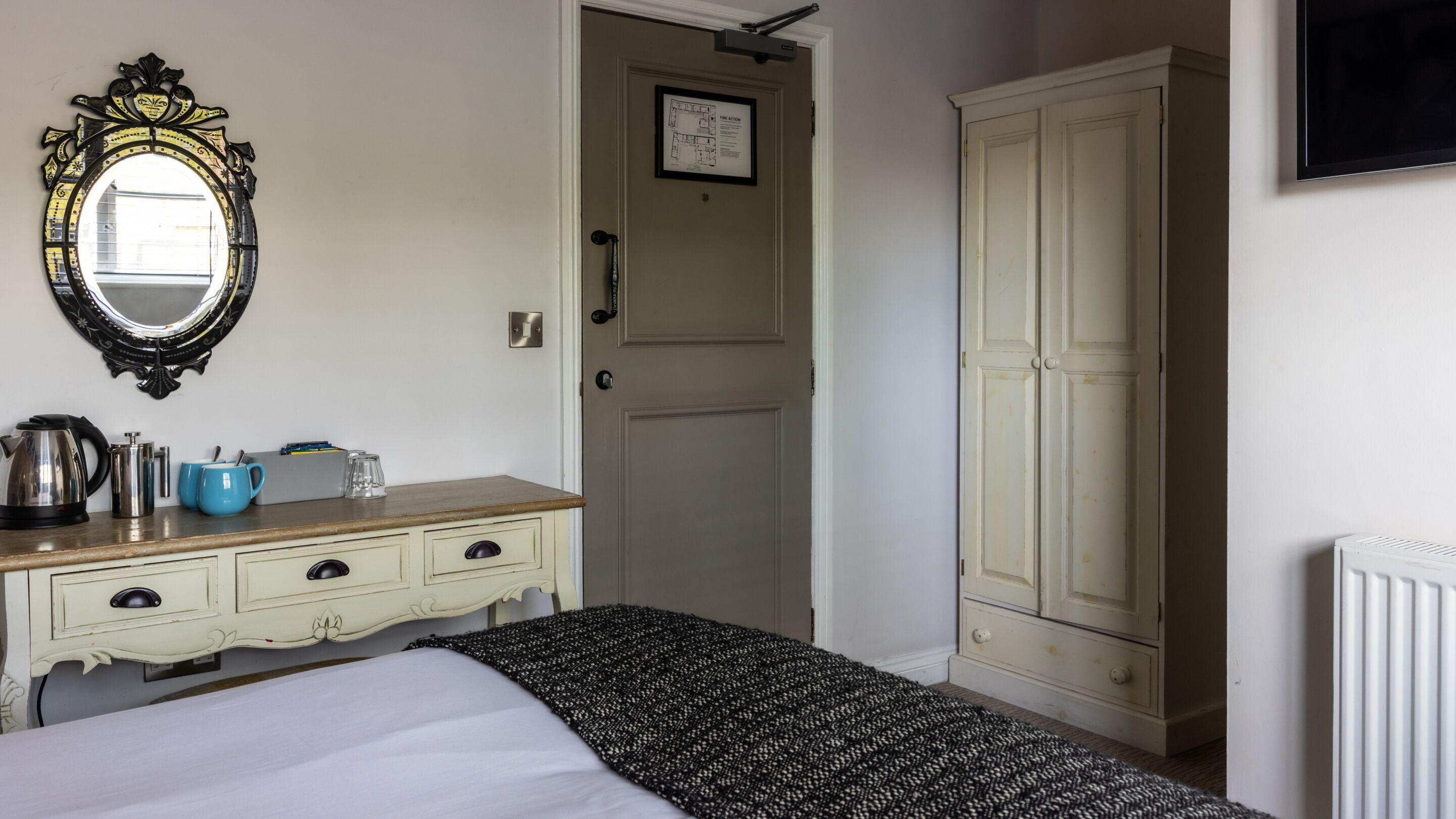 Ein Schlafzimmer mit Bett, Kommode, Spiegel und Kleiderschrank.