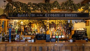 A bar with a 'Welcome to the Croft & Horns' sign, various liquor bottles, and a beer tap. - The Crown & Horns (Newbury)