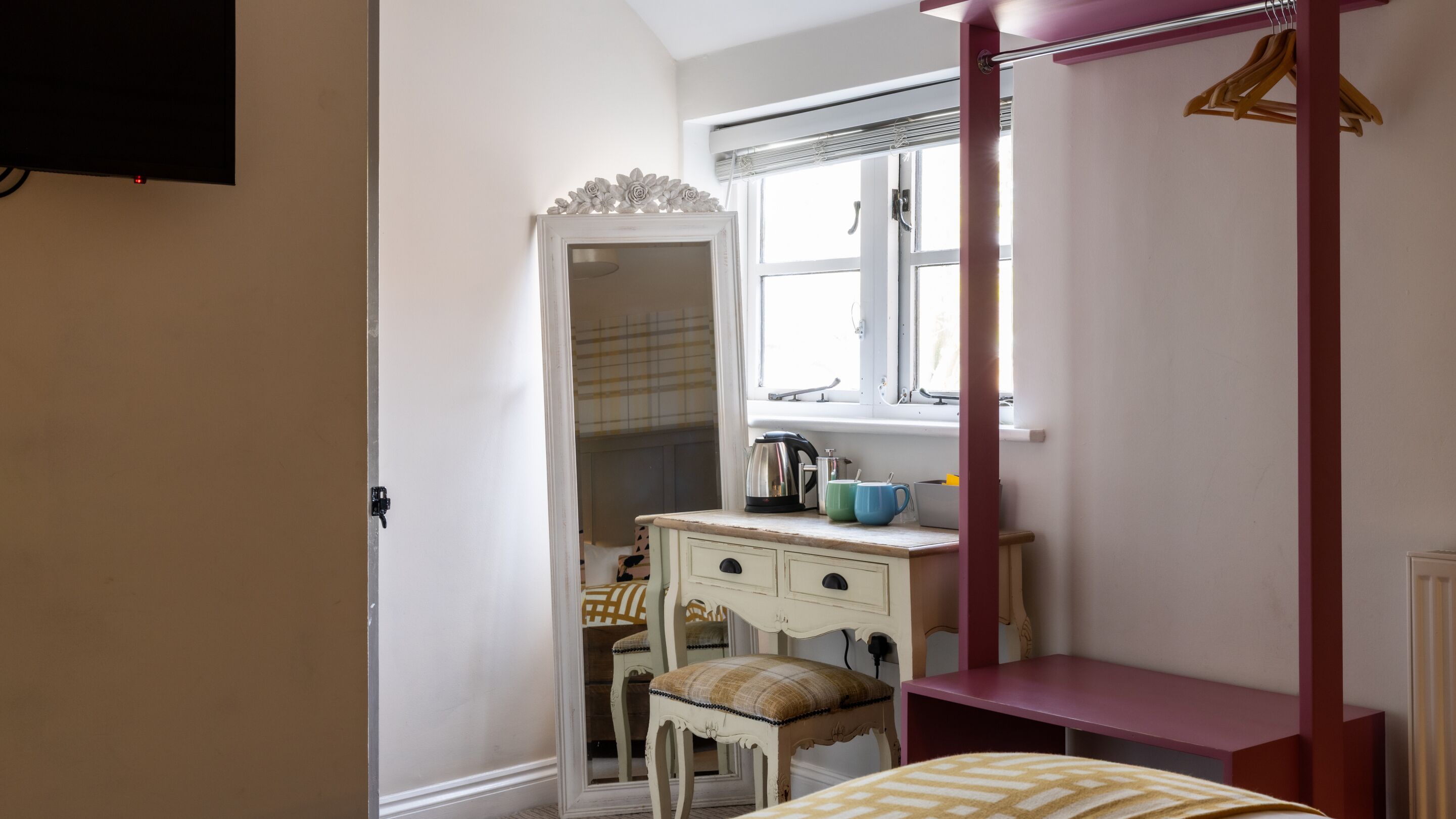 Ein Schlafzimmer mit einem Bett, einem Schminktisch, einem Fenster und einem Hängekorbsessel.