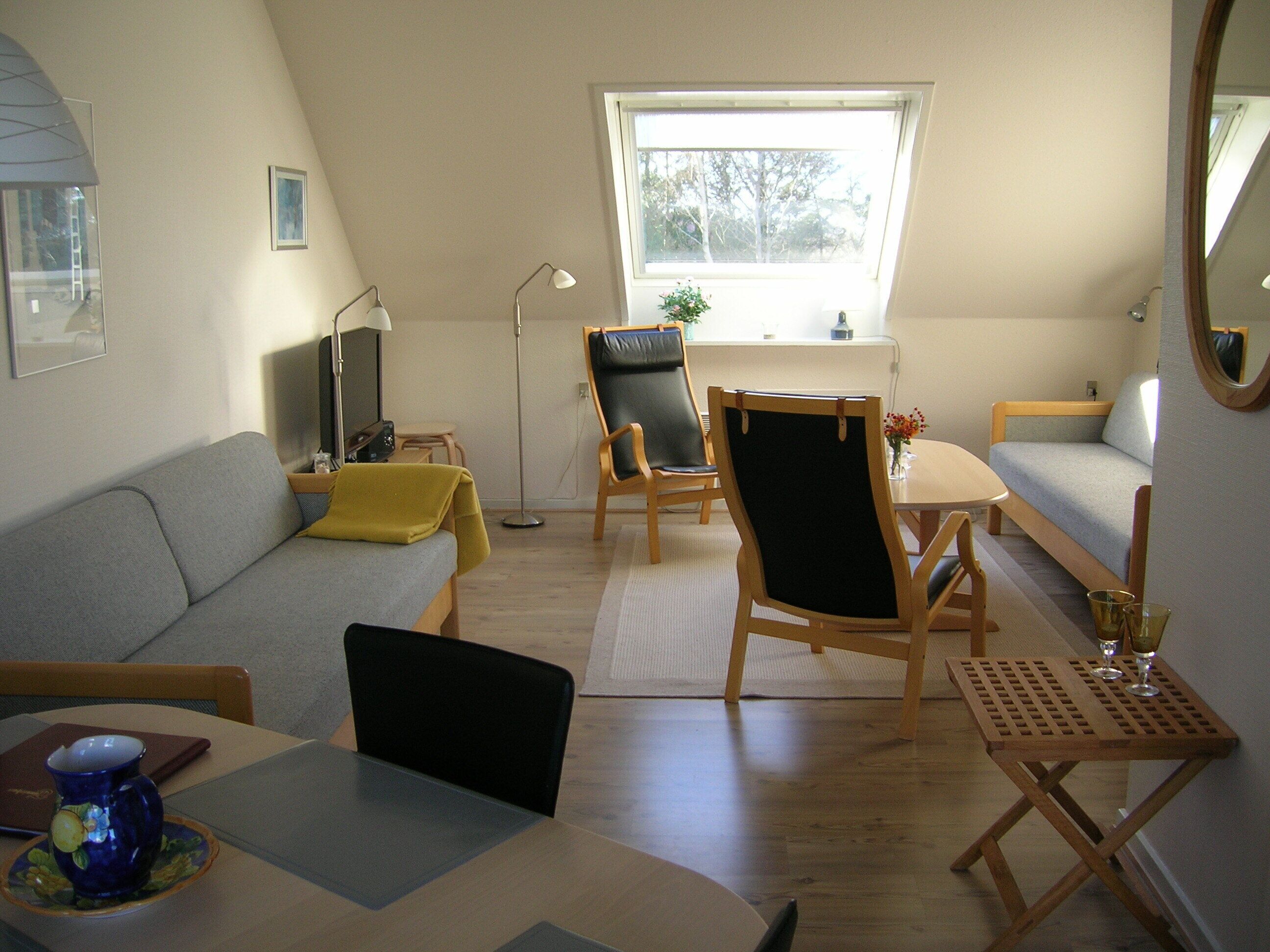 Un espacio habitable compacto con sofá, mesa de comedor, silla, escritorio pequeño y ventana.