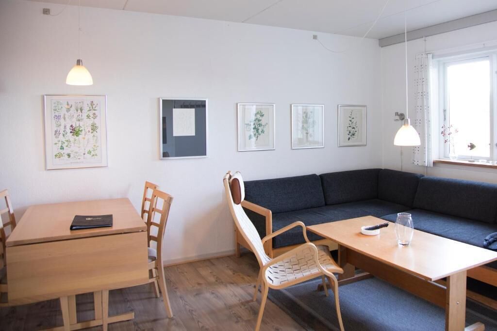 A room with a wooden table, chairs, a sofa, and a window.