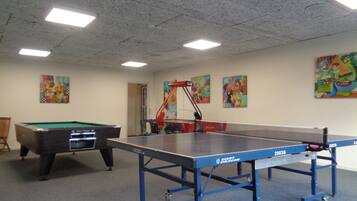 A room with a pool table, a ping pong table, and a billiards table.