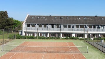 Una cancha de tenis con una red, rodeada por una valla.