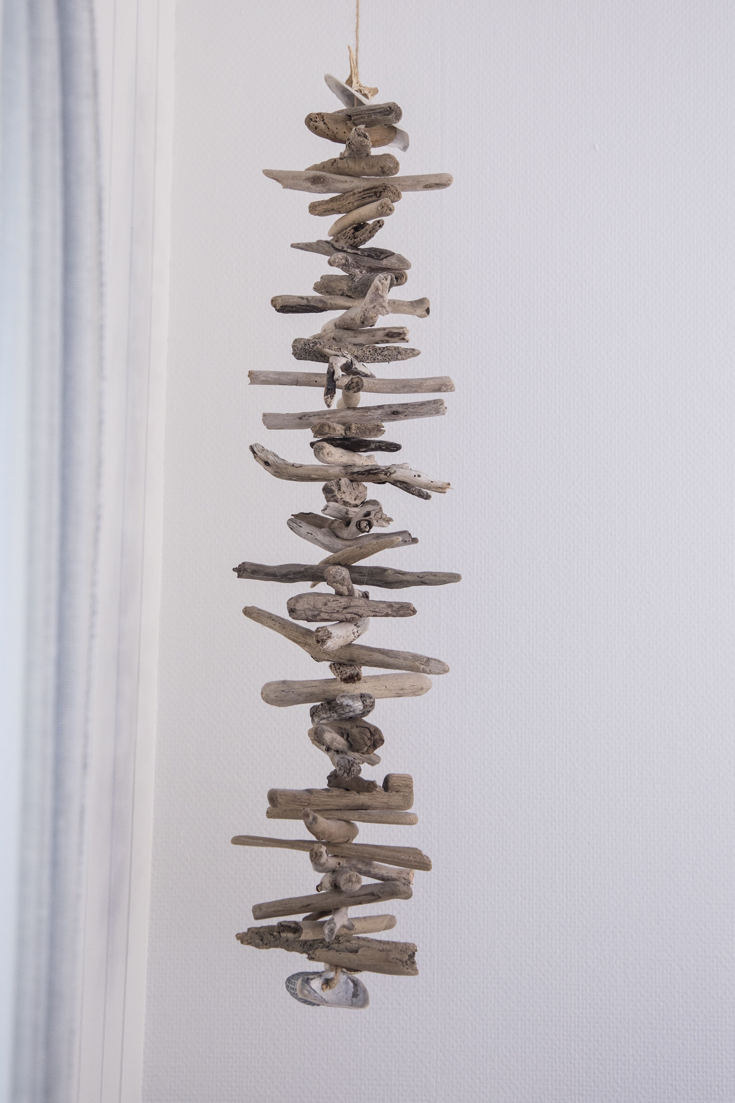 A vertical arrangement of natural wood pieces hanging on a wall.