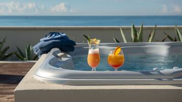 Un bain à remous avec deux boissons, une serviette et une vue sur l’océan.
