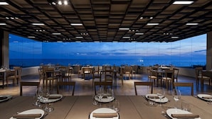Un restaurante con mesas preparadas para comer, con vista al océano.