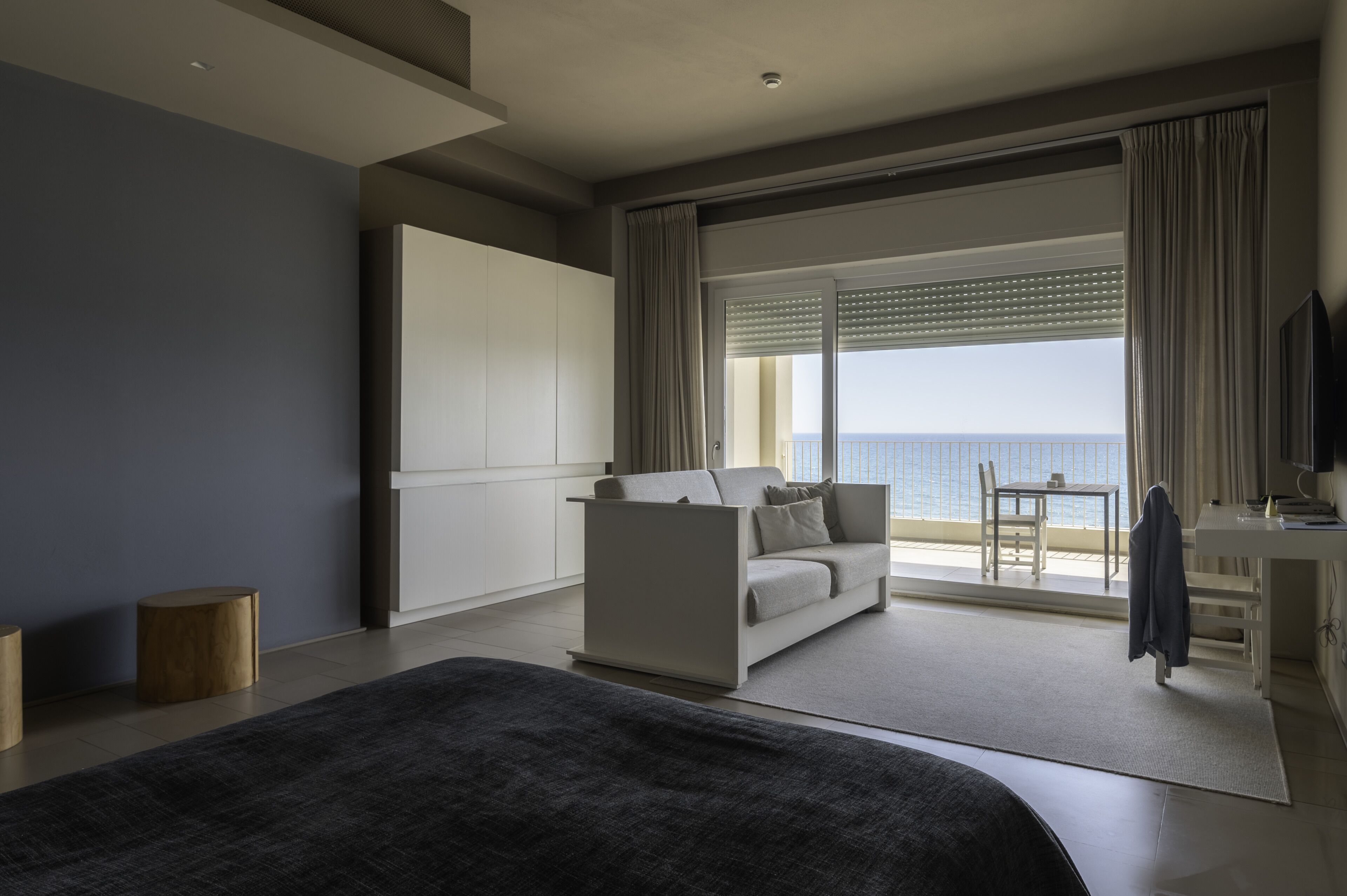 Ein modernes Hotelzimmer mit einem großen Bett, einer Couch, einem Schreibtisch und Meerblick.