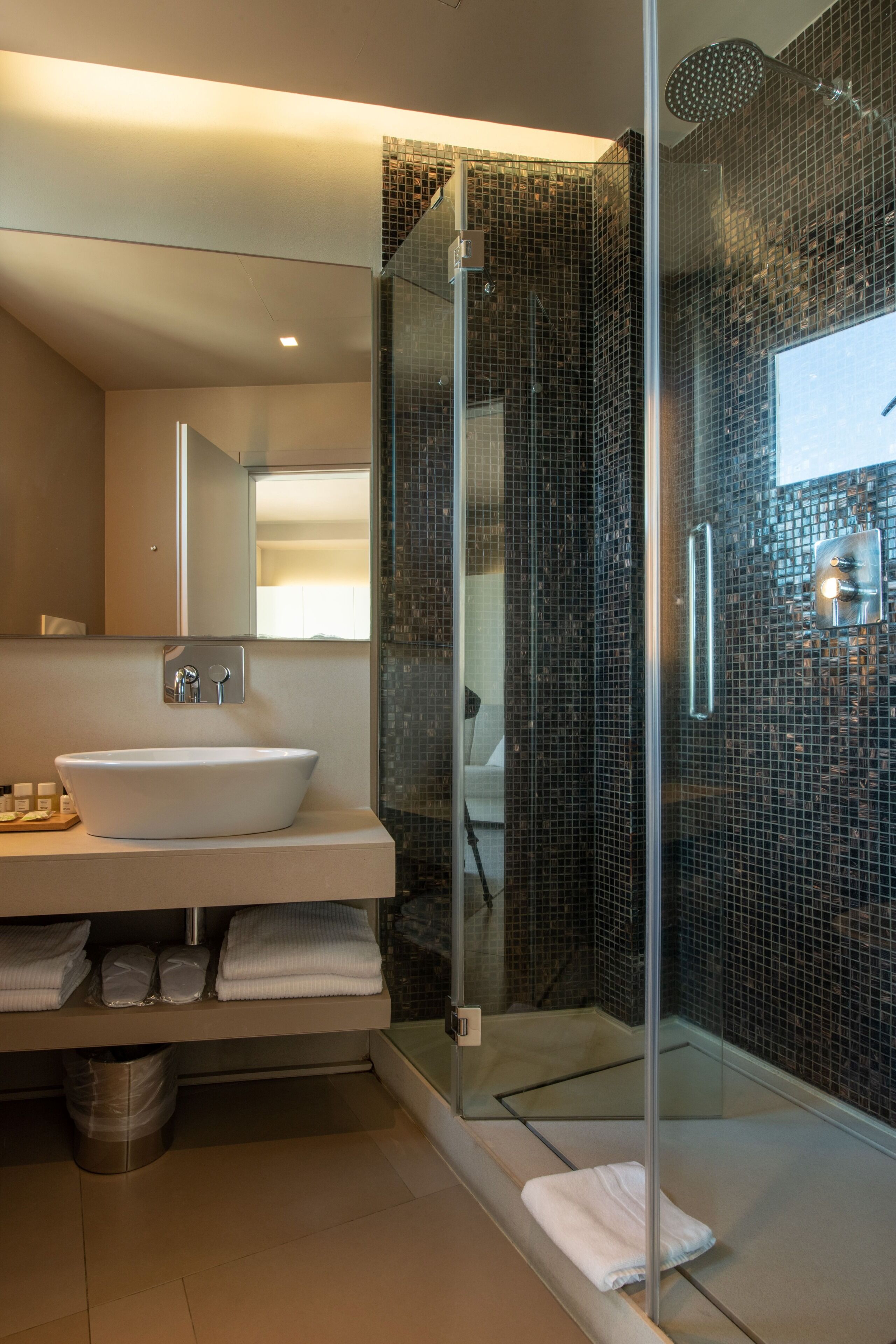 Une salle de bain moderne avec une douche à parois de verre, un lavabo blanc et un miroir au-dessus.
