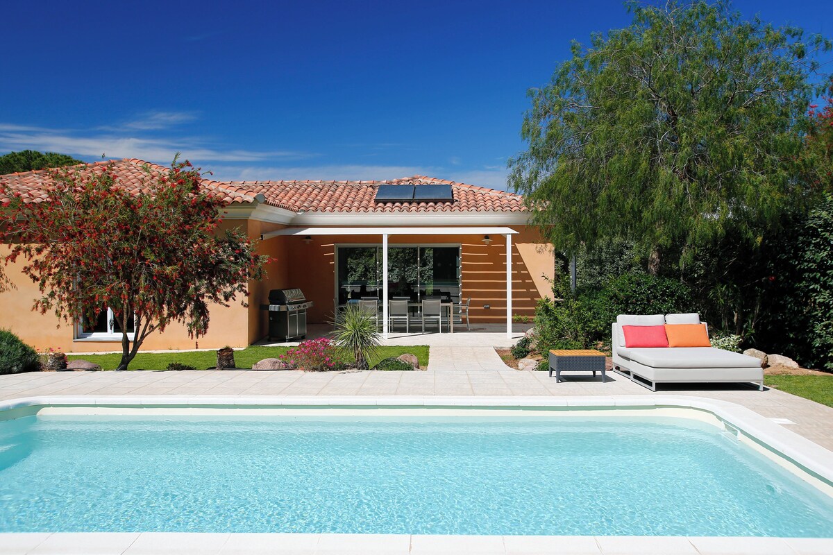 Ein modernes Haus mit Swimmingpool, Sitzgelegenheiten im Freien und einer Terrassenfläche.