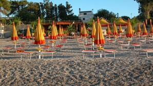 Una playa con numerosos sombrillas y tumbonas dispuestas en filas.