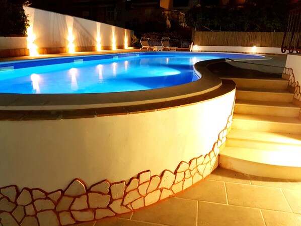 A swimming pool with a stone border and steps leading down to the water. - Hotel Alexander (Giardini Naxos)