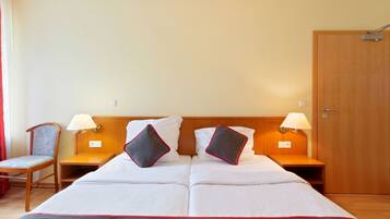 A hotel room with a large bed, two bedside tables, two lamps, a chair, and a wooden door.