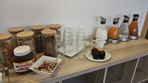 Un comptoir de petit-déjeuner avec des bocaux de granola, un pot de Nutella et une assiette de muffins.