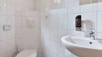 Un baño con inodoro, lavamanos y secamanos.